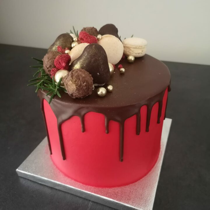 Luxury Christmas Cake with red buttercream, chocolate drip and sweets on top.