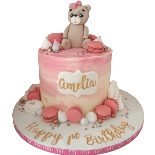 Pink Teddy Bear Cake with a fondant teddy, macaroons, meringues and sprinkles.